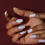 a woman's hands with white nail polish on them
