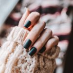 person with black manicure holding white textile