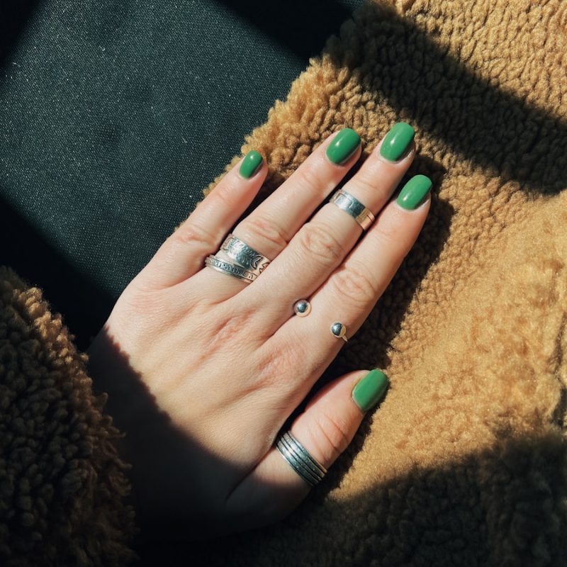 person wearing silver ring with green manicure